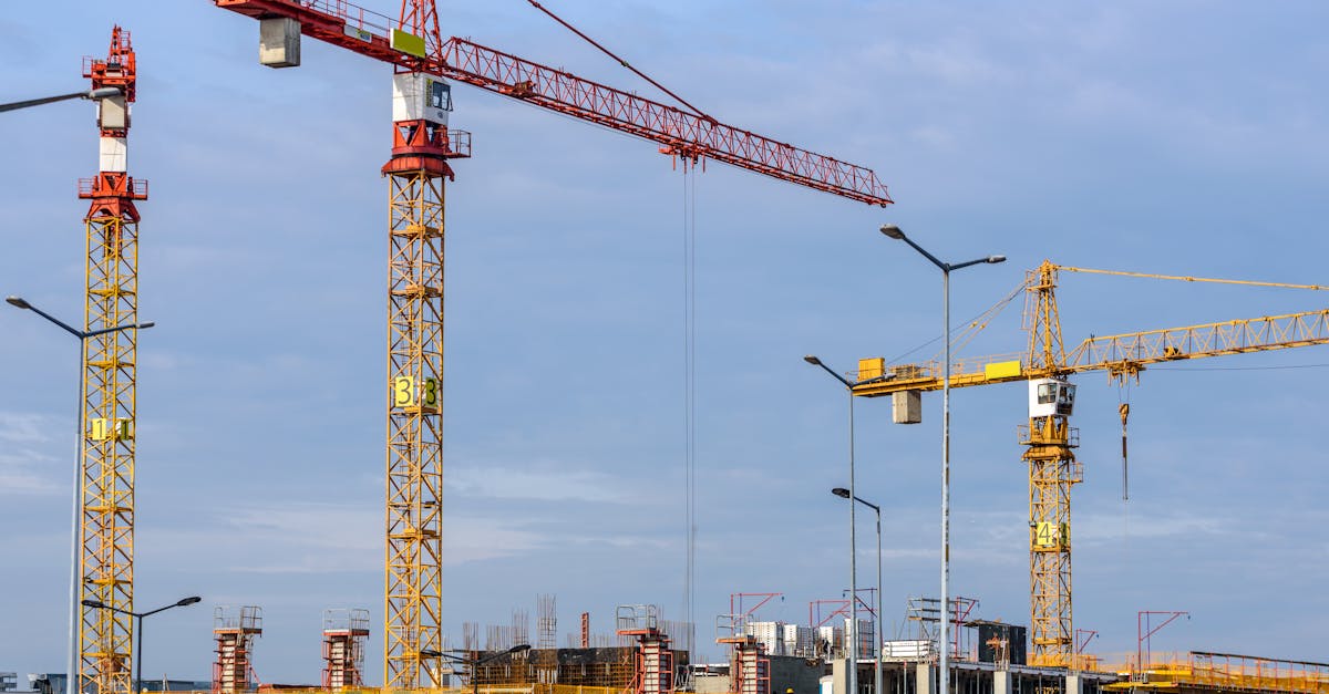 Three Yellow and Red Tower Cranes Under Clear Blue Sky